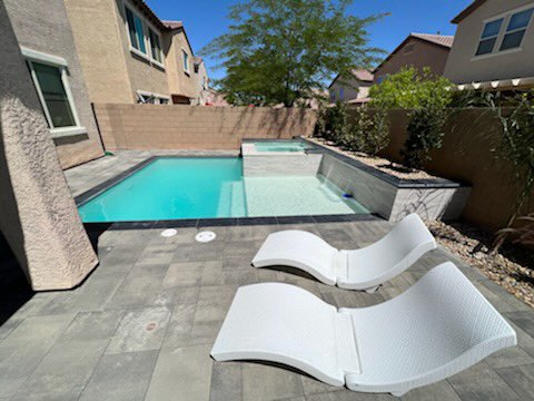 Two lounge chairs sit next to a pool